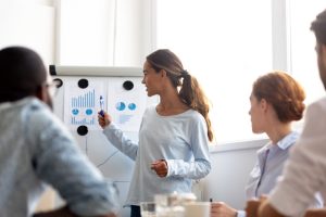 Woman pointing to graphs on a white board