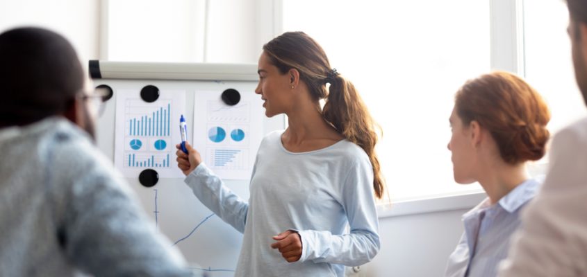 Woman pointing to graphs on a white board